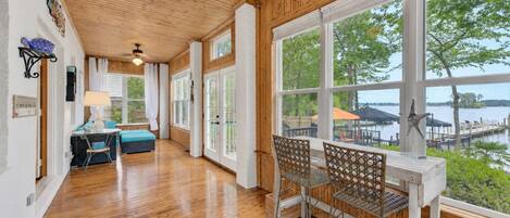A spacious room with wooden floors, large windows, and a view of a dock and water.