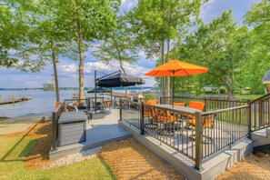 Eine Terrasse mit Sitzgelegenheiten im Freien, einem Grill und Blick auf das Wasser.