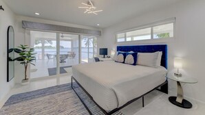 Ein modernes Schlafzimmer mit einem großen Bett, einem verglasten Balkon und Blick ins Freie.