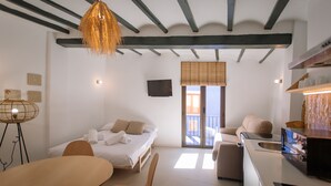 A modern hotel room with a bed, a dining table, a sofa, a kitchen area, and a balcony with a view. - Alojamientos La Vila Mayor 36 (Villajoyosa)