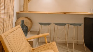 A cozy room with a wooden chair, a small table, and a bar area with stools. - Alojamientos La Vila Mayor 36 (Villajoyosa)
