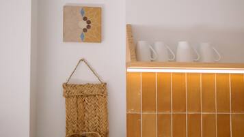 A bathroom with a sink, a woven basket, and two wall-mounted artworks.