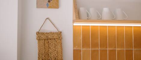 Un bagno con un lavandino, un cesto in vimini e due opere d'arte appese al muro.