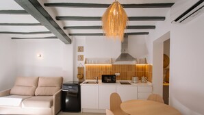 A modern kitchen with white cabinets, a black refrigerator, and a dining area with a round table and chairs. - Alojamientos La Vila Mayor 36 (Villajoyosa)
