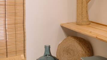Una habitación con una silla, una mesa, un pouf y un cactus decorativos, todos tejidos, junto con un jarrón azul.