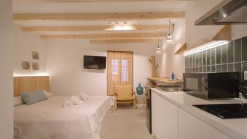 A compact hotel room with a bed, a small desk, a microwave, and a TV.