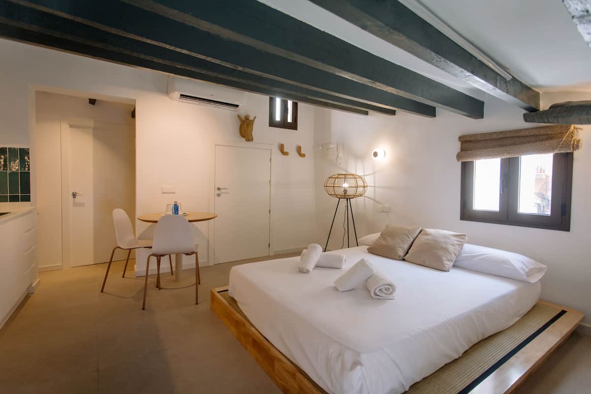 A bedroom with a bed, a desk, chairs, and a small table.