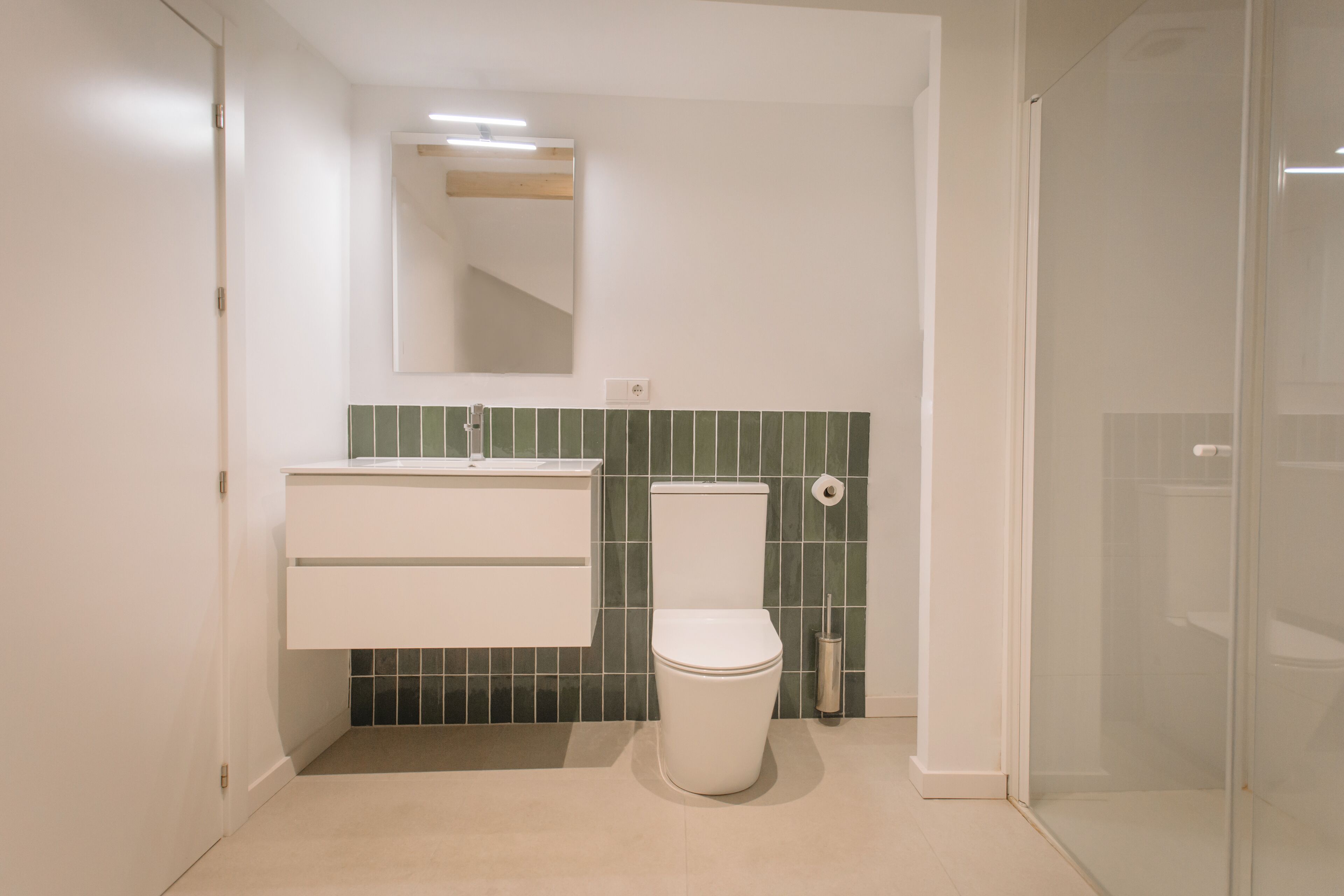 Un baño moderno con inodoro, lavamanos y espejo.