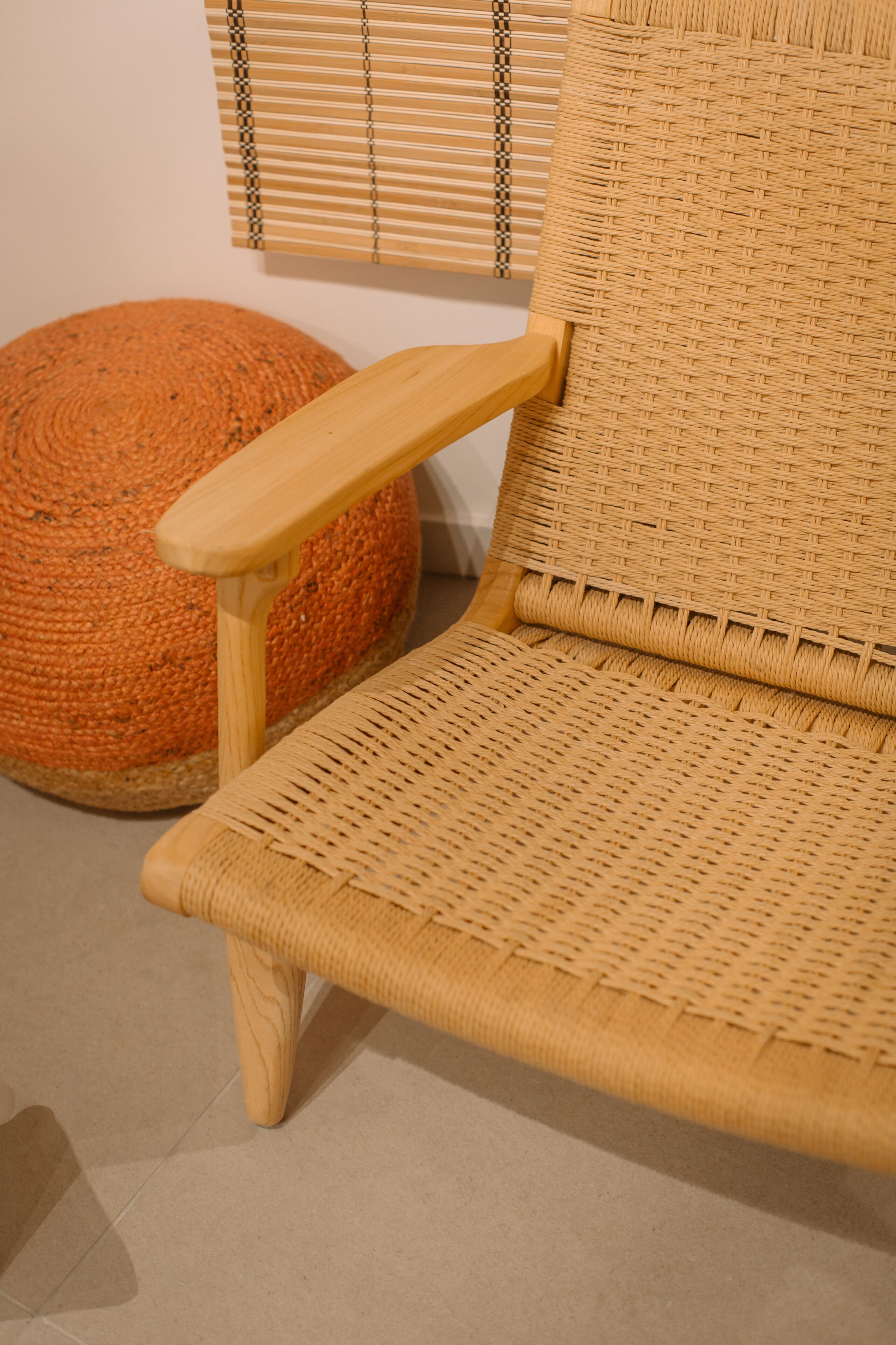 A wicker chair with a wooden armrest and a woven ottoman.