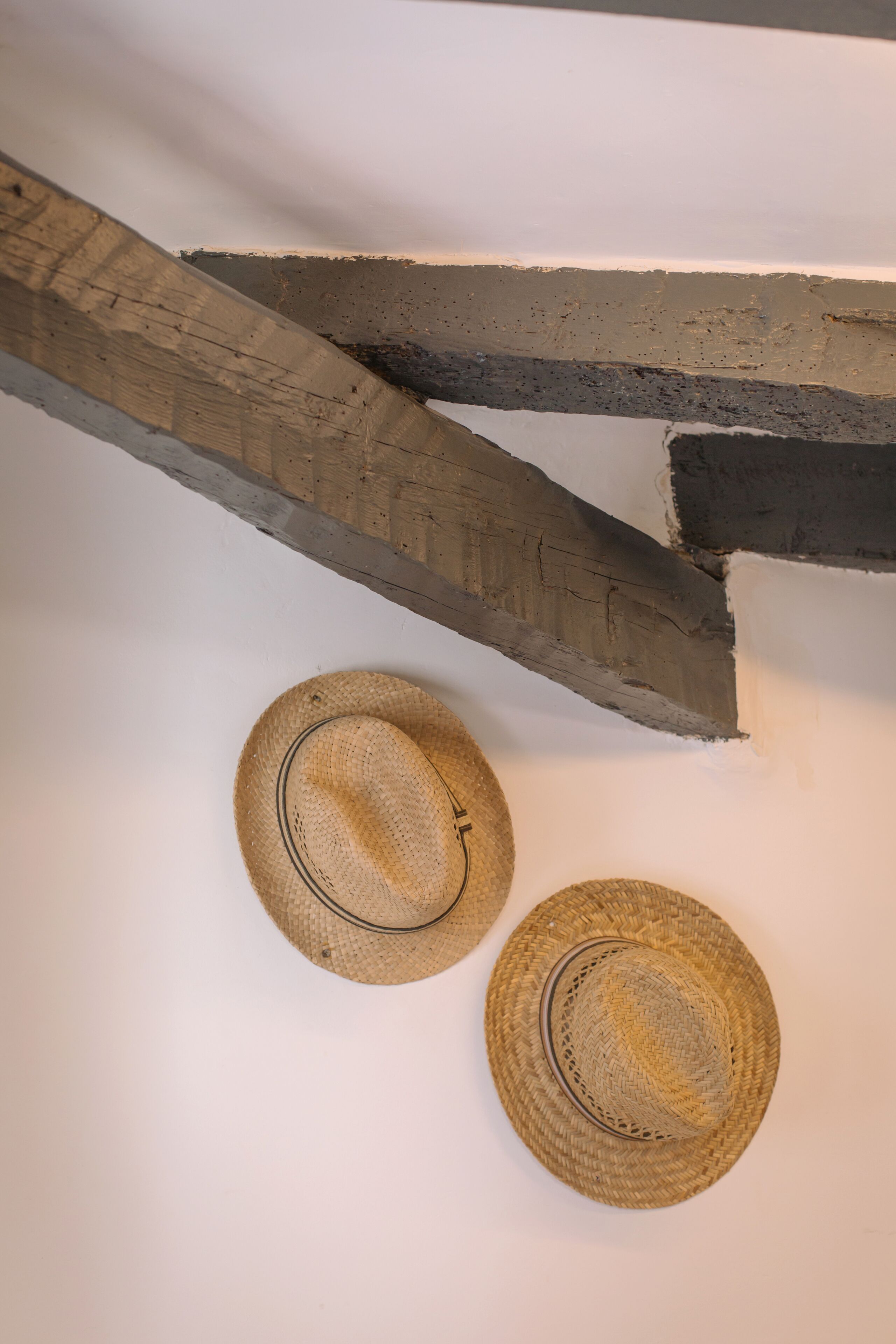 Dos sombreros de paja sobre una pared blanca.