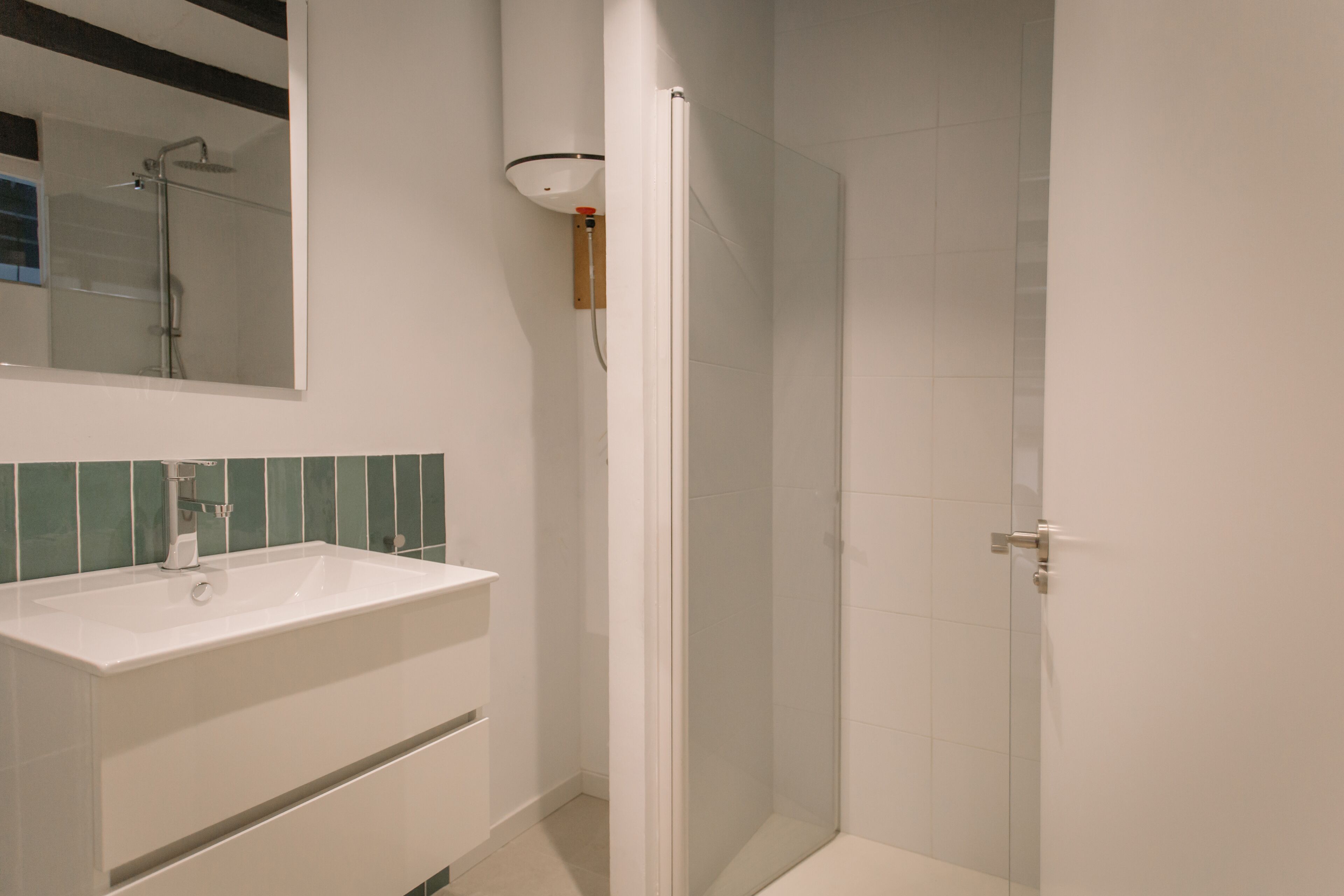 A bathroom with a white sink, mirror, and shower enclosure.