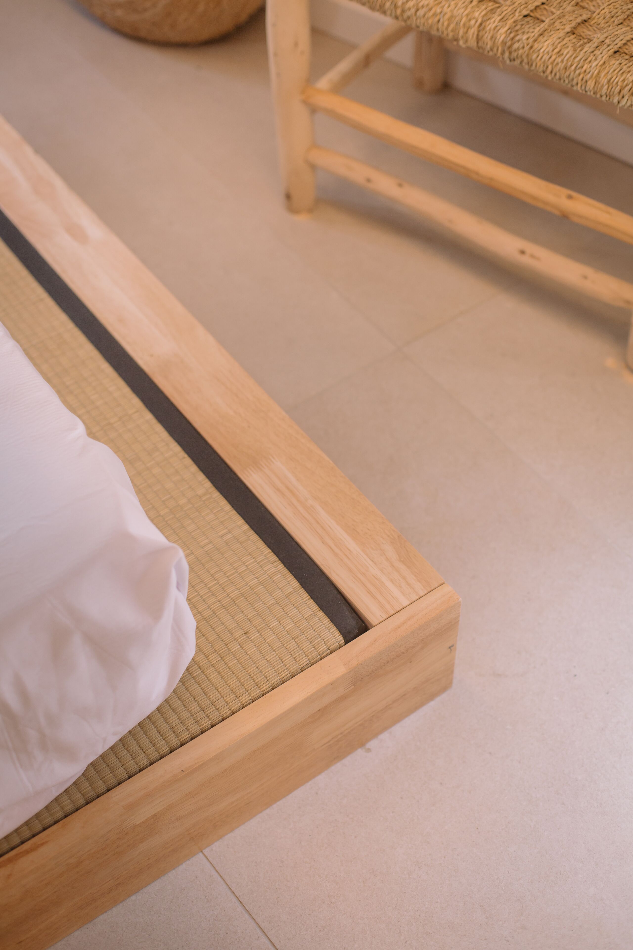 Una cama de madera con un colchón tejido y una almohada blanca.