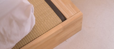 A wooden bed with a woven mat and a white pillow.