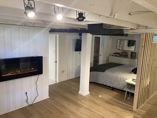 A bedroom with a bed, a TV, a desk, and a mirror.