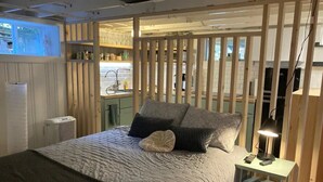 Ein Schlafzimmer mit einem Bett, einem Nachttisch mit Lampe und einer Holzwand.