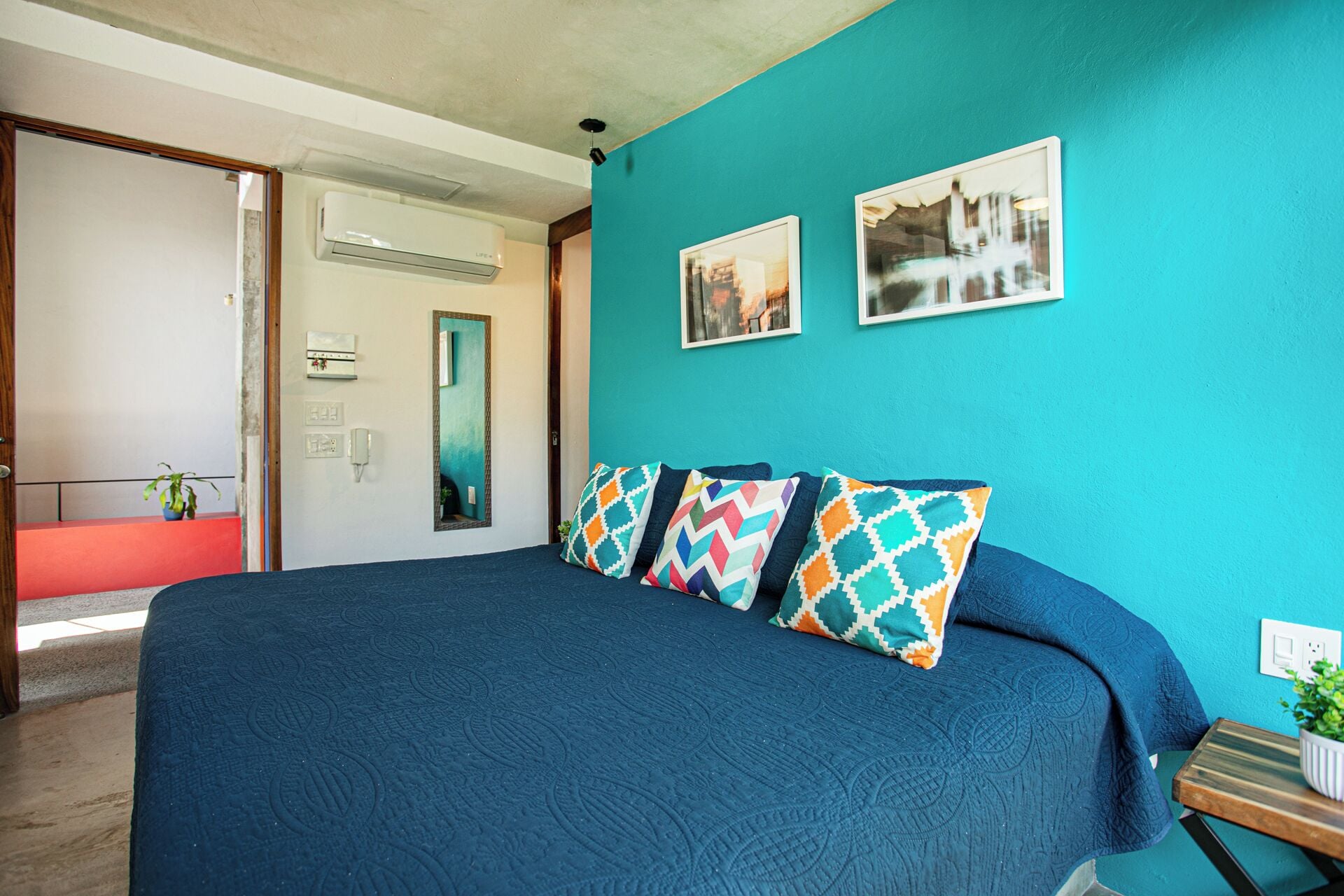 Une chambre à coucher avec un grand lit, des murs de couleur turquoise et deux tableaux encadrés.