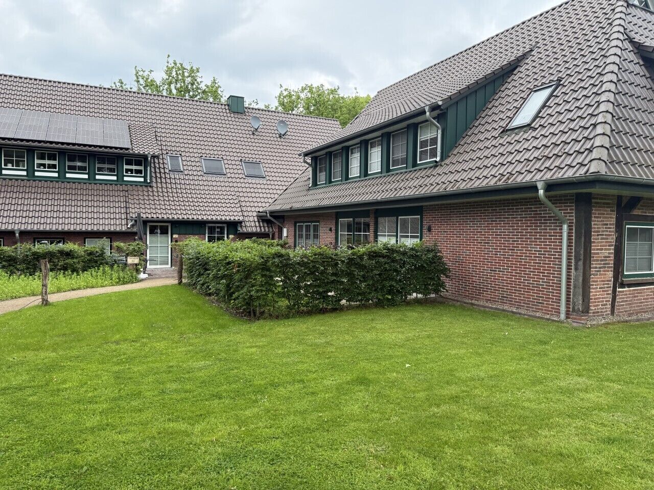 Een woongebouw met een schuin dak, veel ramen en een verzorgd gazon.