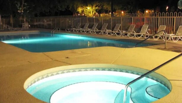 Ein Schwimmbad mit Liegestühlen und einem Whirlpool bei Nacht.