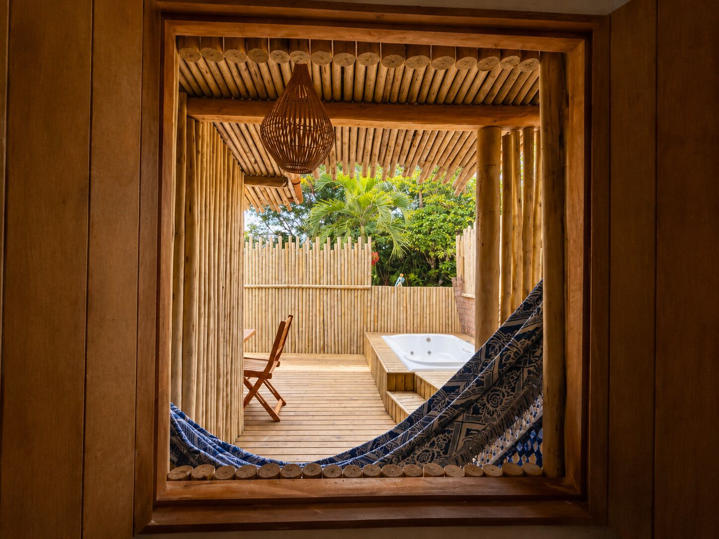Una habitación de madera con una hamaca, un banco de madera y una lámpara colgante.
