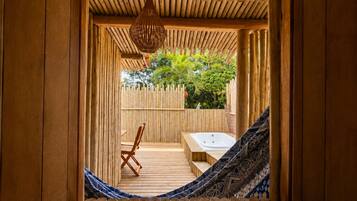 Una habitación de madera con una hamaca, un banco de madera y una lámpara colgante.