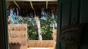 Una terraza de madera al aire libre con un jacuzzi, rodeada de fardos de paja y una estructura cubierta de paja.