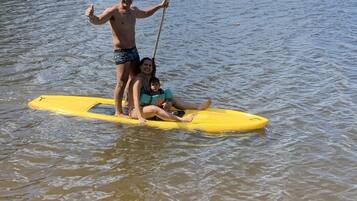 Una persona in piedi su una tavola da paddleboard gialla in acqua, con un remo in mano.