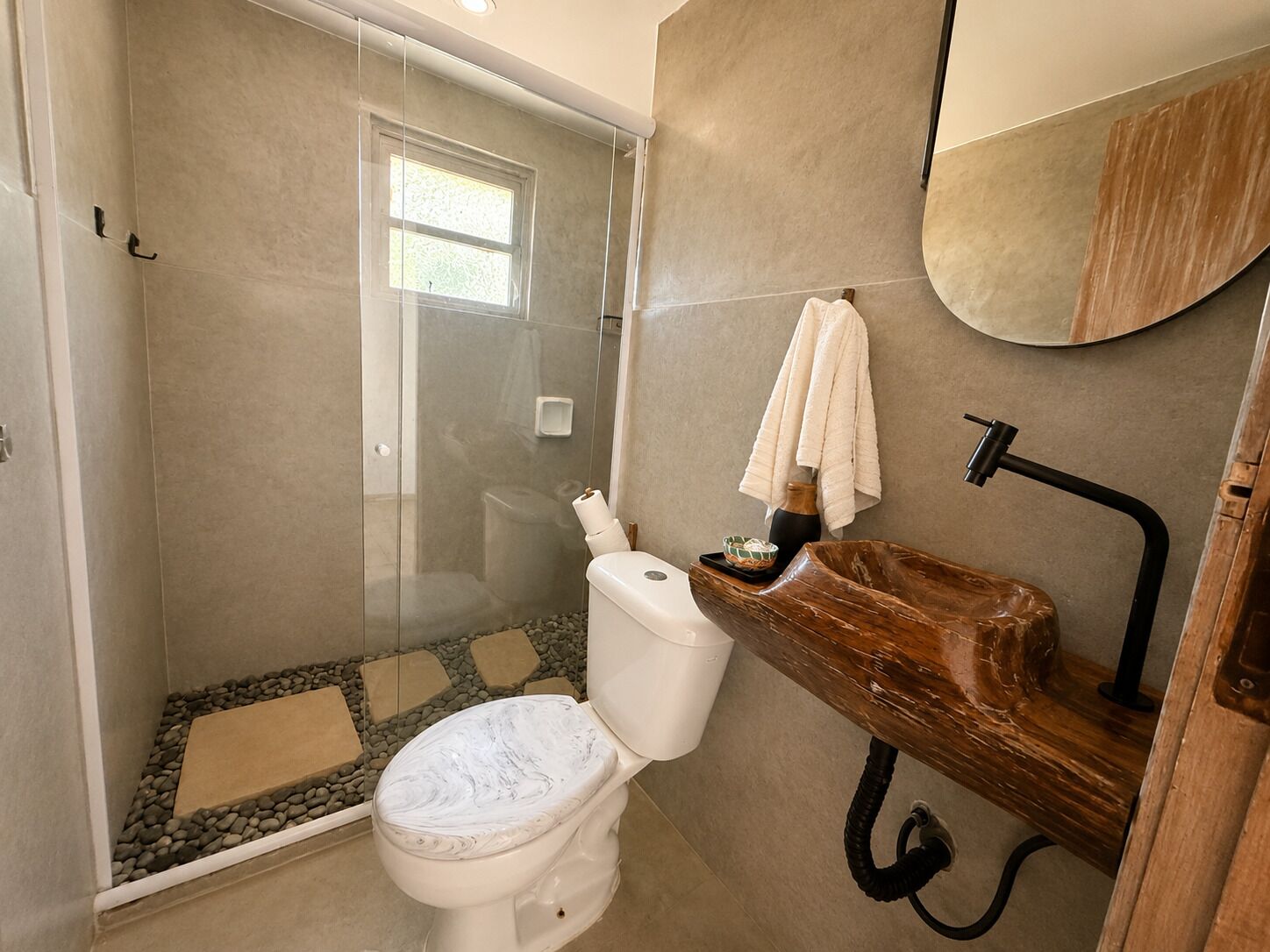 Un bagno con cabina doccia in vetro, un water bianco, un mobile bagno in legno con lavandino e uno specchio.