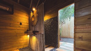 Un interior de madera con una pared de piedra, un banco de madera y un camino de piedra que conduce al exterior.