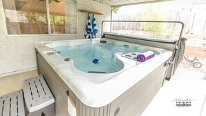 Un bain à remous avec un couvercle, une fenêtre et une serviette à proximité.