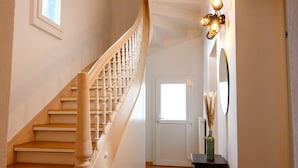 A staircase with wooden steps and white balusters, leading to a door with a window above it.