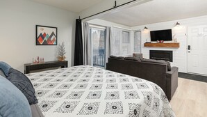 Un dormitorio moderno con una cama grande, un sofá, una chimenea y un televisor.