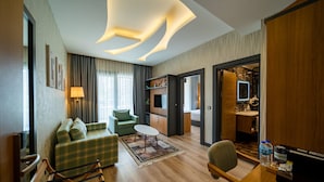 A modern hotel room with a sofa, armchair, and a desk with a computer. - Holiday Inn Trabzon East by IHG (Yomra)