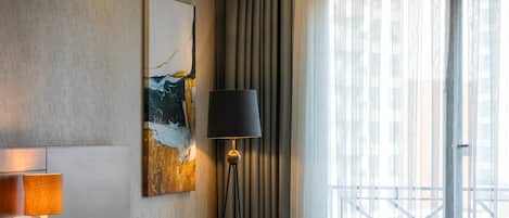 Habitación de hotel con un sofá verde, una mesita redonda pequeña, una lámpara y un cuadro en la pared.