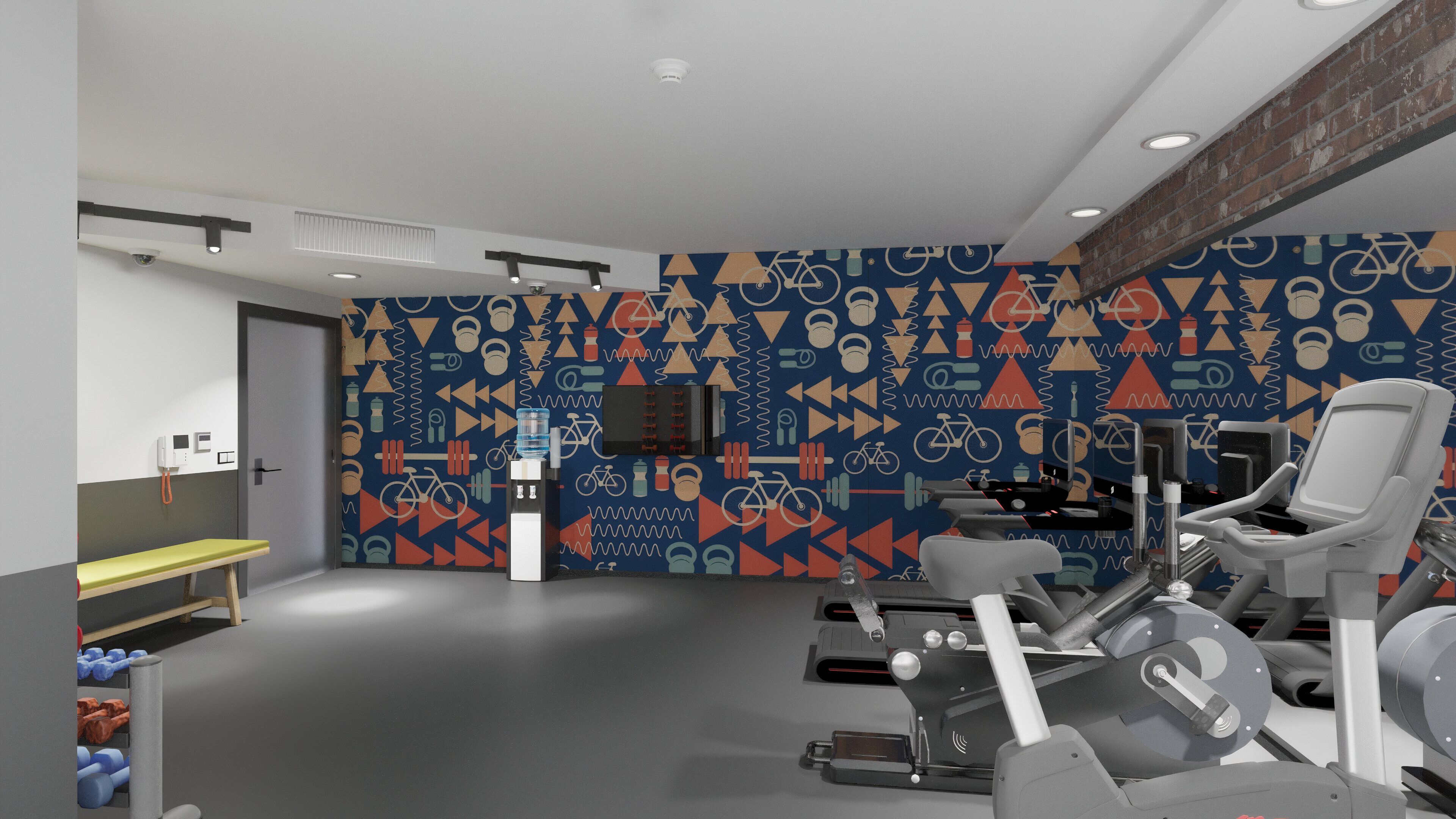 Une salle de sport équipée de matériel d’exercice, d’un distributeur d’eau et d’un mur décoré de motifs.