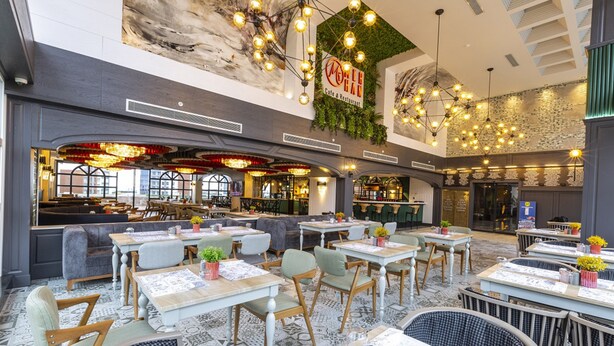 A modern restaurant interior with high ceilings, exposed brick walls, and a variety of seating options including tables and booths. - Holiday Inn Trabzon East by IHG (Yomra)