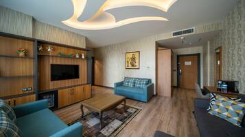 A modern living room with a flat-screen TV, blue sofa, wooden cabinets, and a patterned rug.