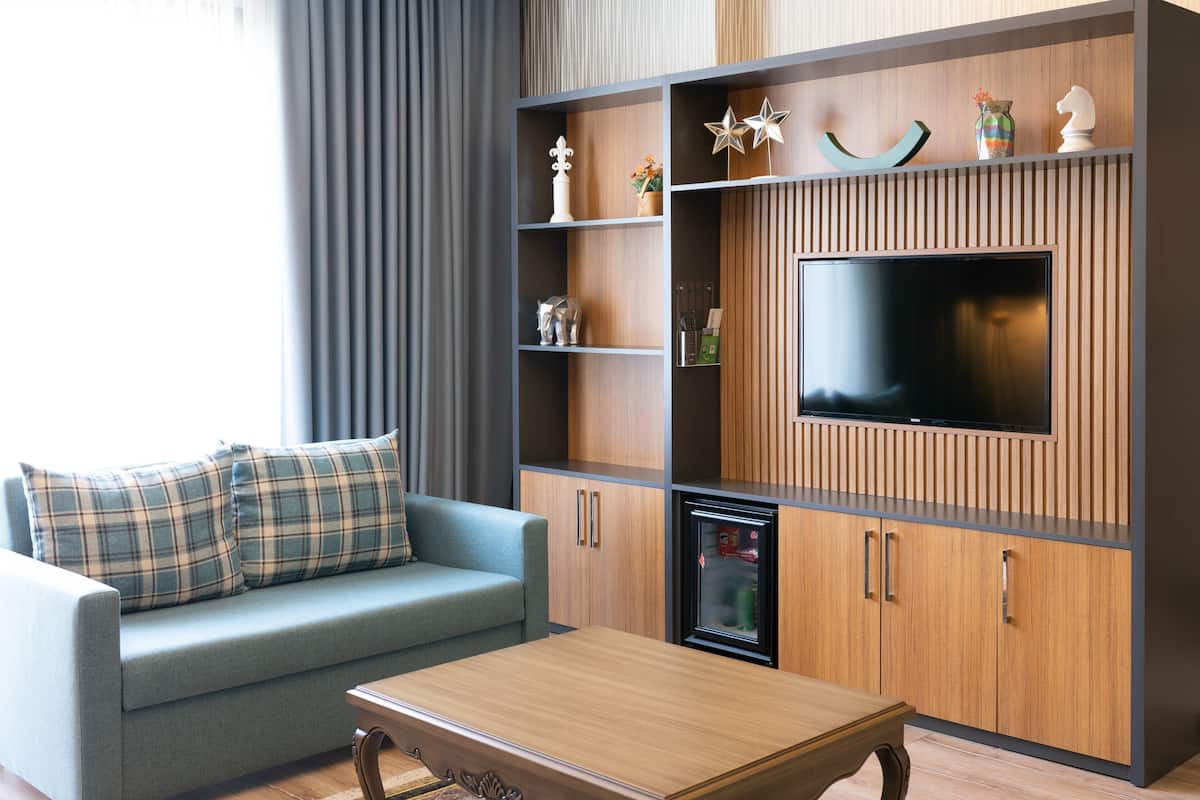 Un salon moderne comprenant un canapé, une table basse, un téléviseur et des étagères intégrées ornées d’objets décoratifs.