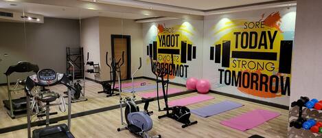 A gym with exercise equipment, mats, and motivational wall art.