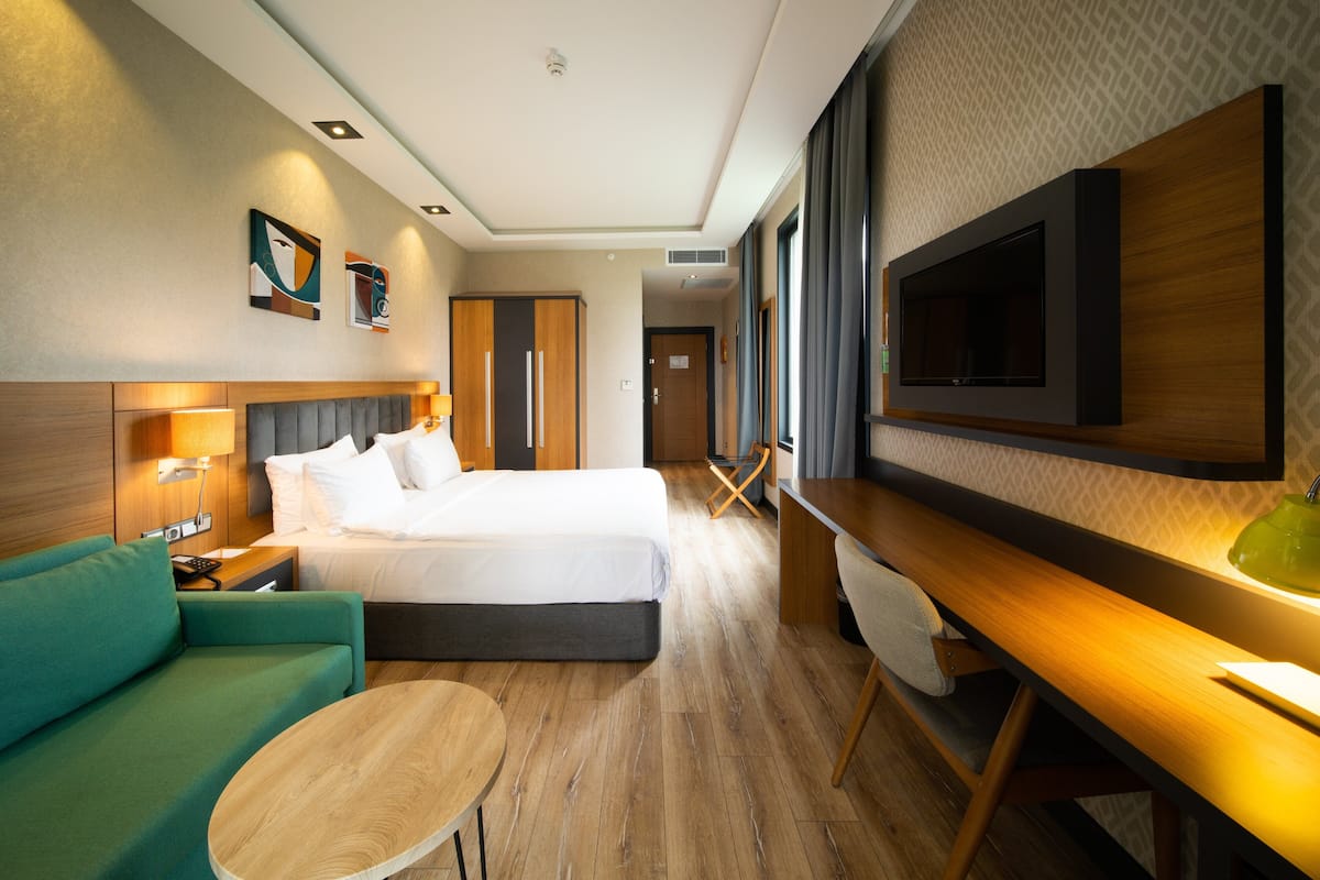 Une chambre d’hôtel moderne équipée d’un lit, d’un bureau, d’un canapé et d’un téléviseur fixé au mur.
