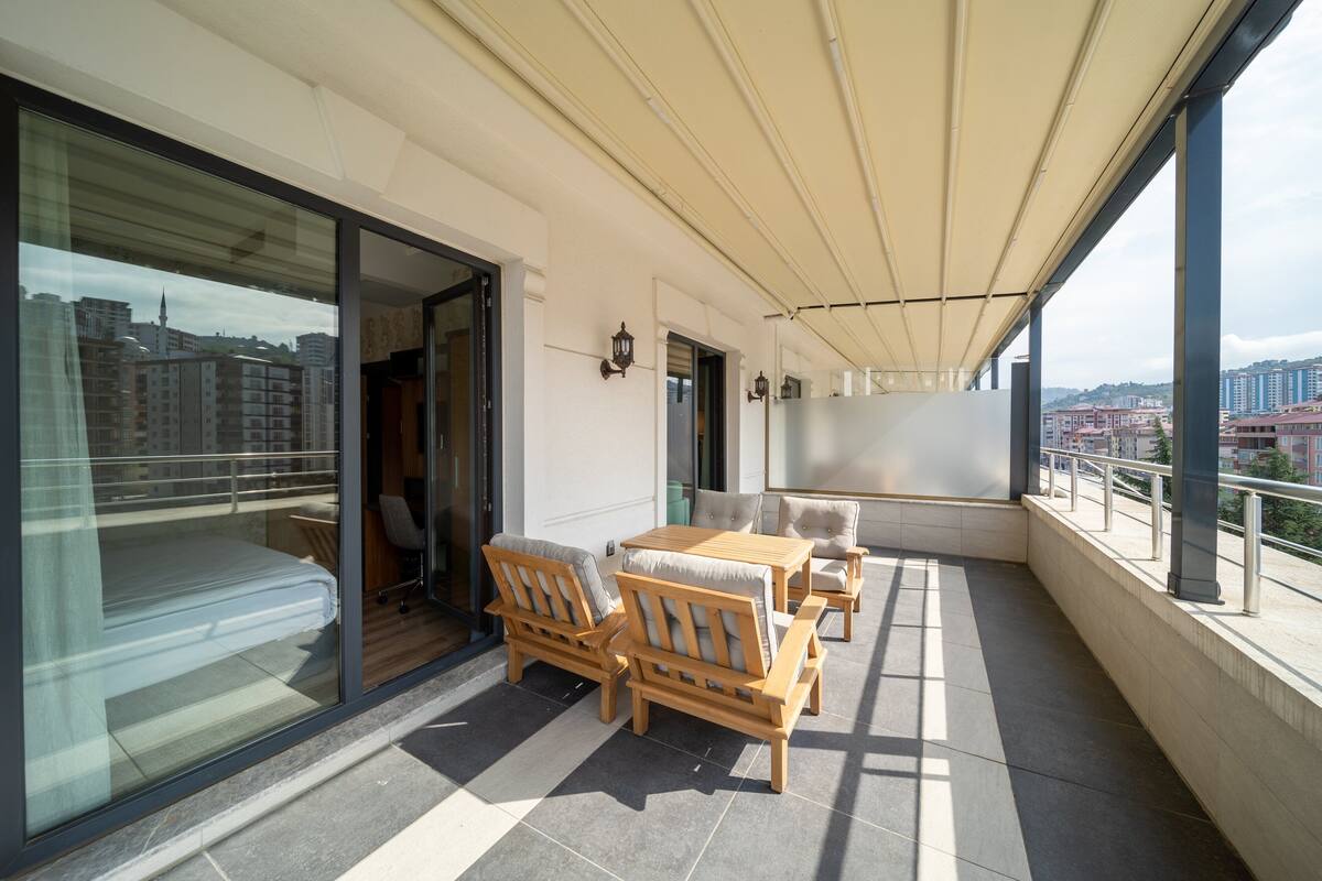 Un balcon avec une table et des chaises en bois, un canapé et un lit.