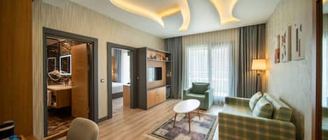 Una habitación de hotel moderna con suelo de madera, un sofá verde, una pequeña mesa redonda y un techo con una lámpara original.