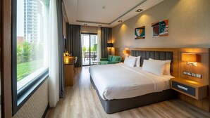 A modern hotel room with a large bed, a seating area with a table, and a view of the outdoors. - Holiday Inn Trabzon East by IHG (Yomra)