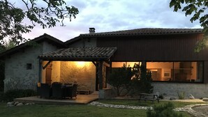 A modern house with a stone exterior, a patio with outdoor furniture, and a well-maintained lawn.