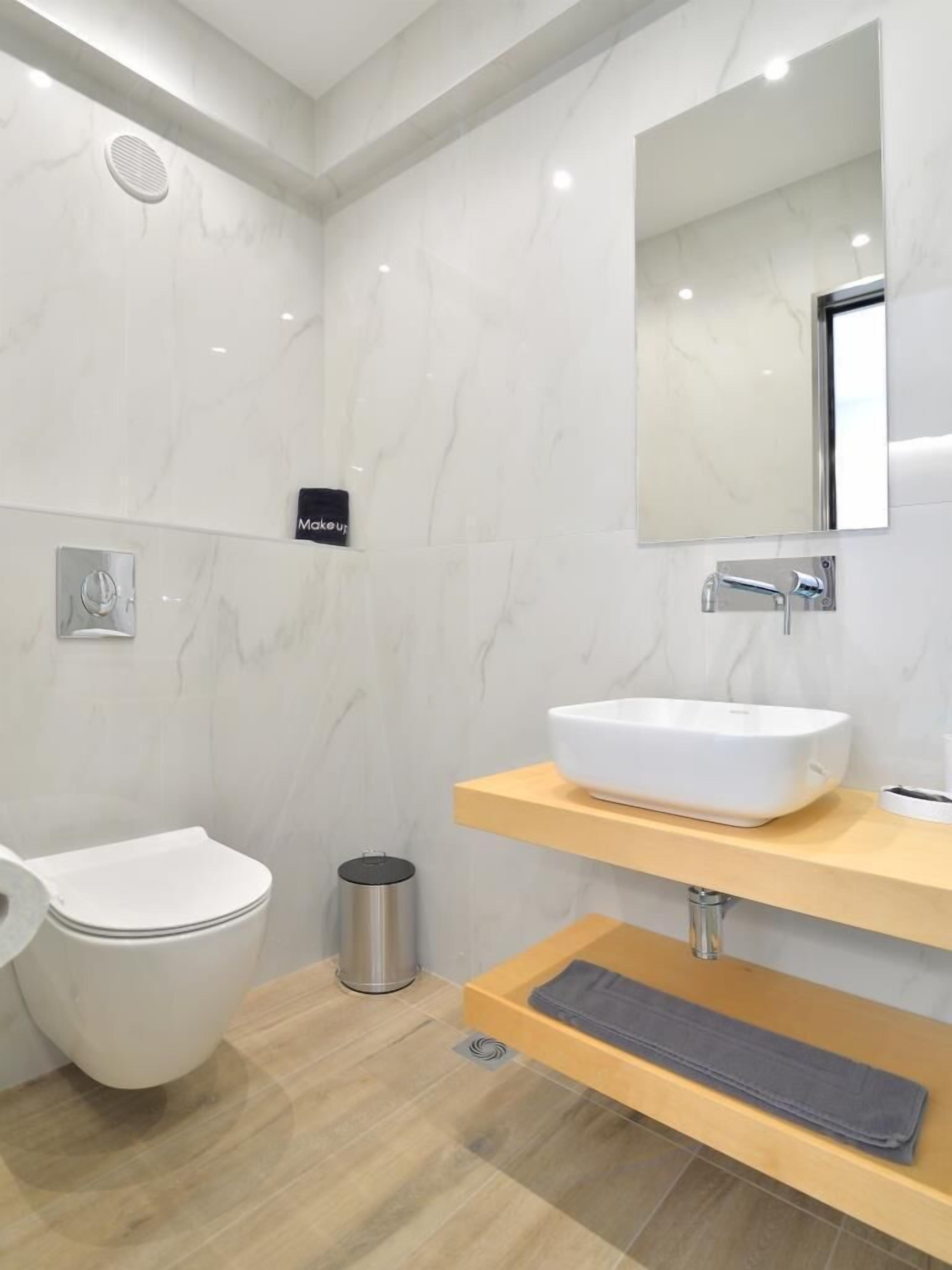 A modern bathroom with a toilet, sink, and mirror.