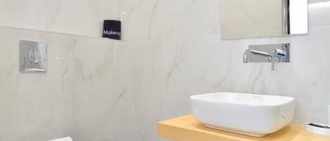 A modern bathroom with a toilet, sink, and mirror.