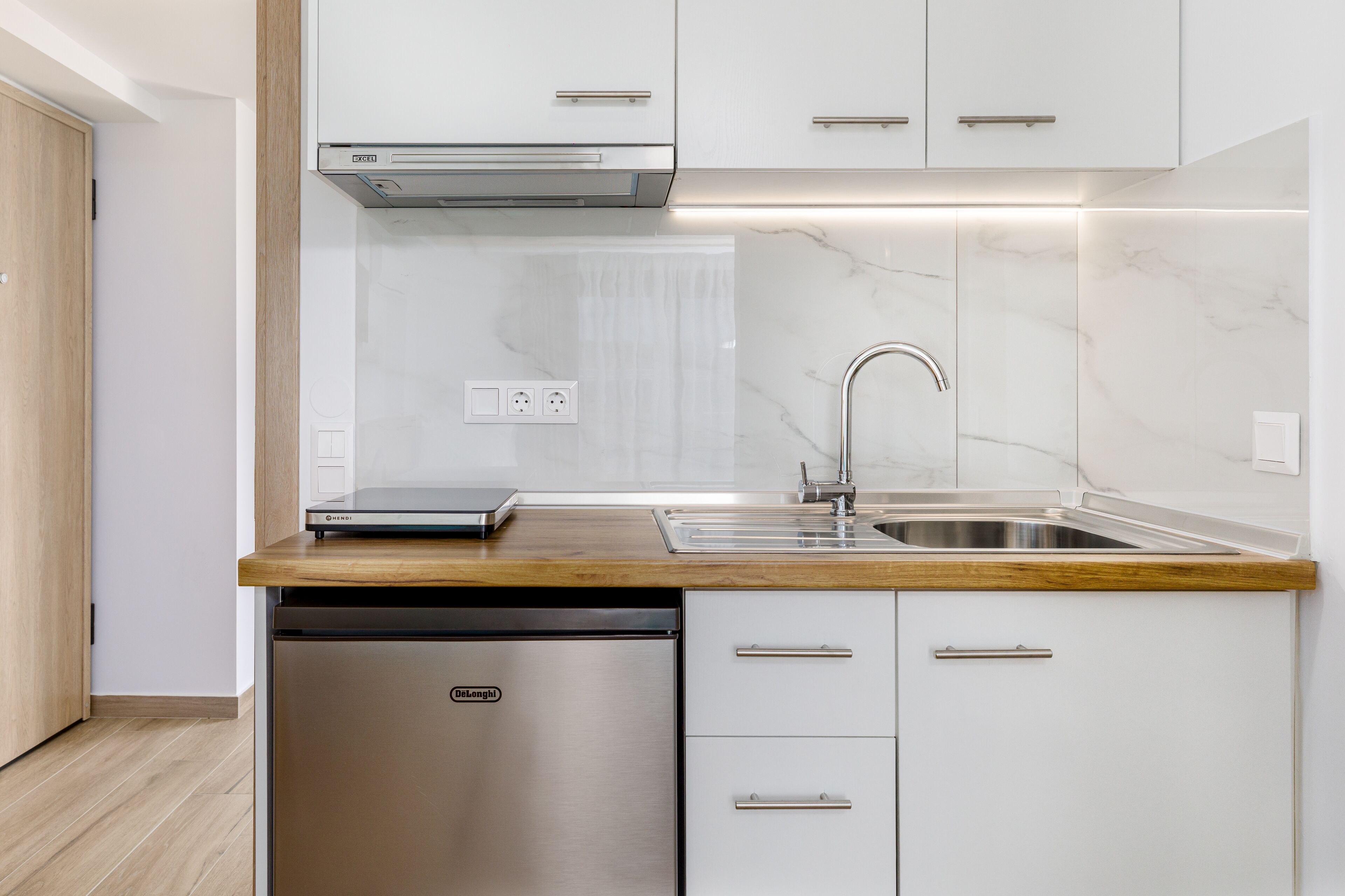 Una cocina moderna con armarios blancos, lavavajillas de acero inoxidable y encimera de madera.