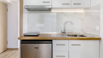 Una cocina moderna con armarios blancos, lavavajillas de acero inoxidable y encimera de madera.