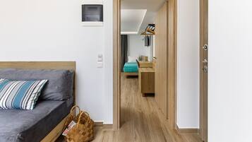 Una habitación con una cama, una puerta de madera, una mesita pequeña y un perchero.