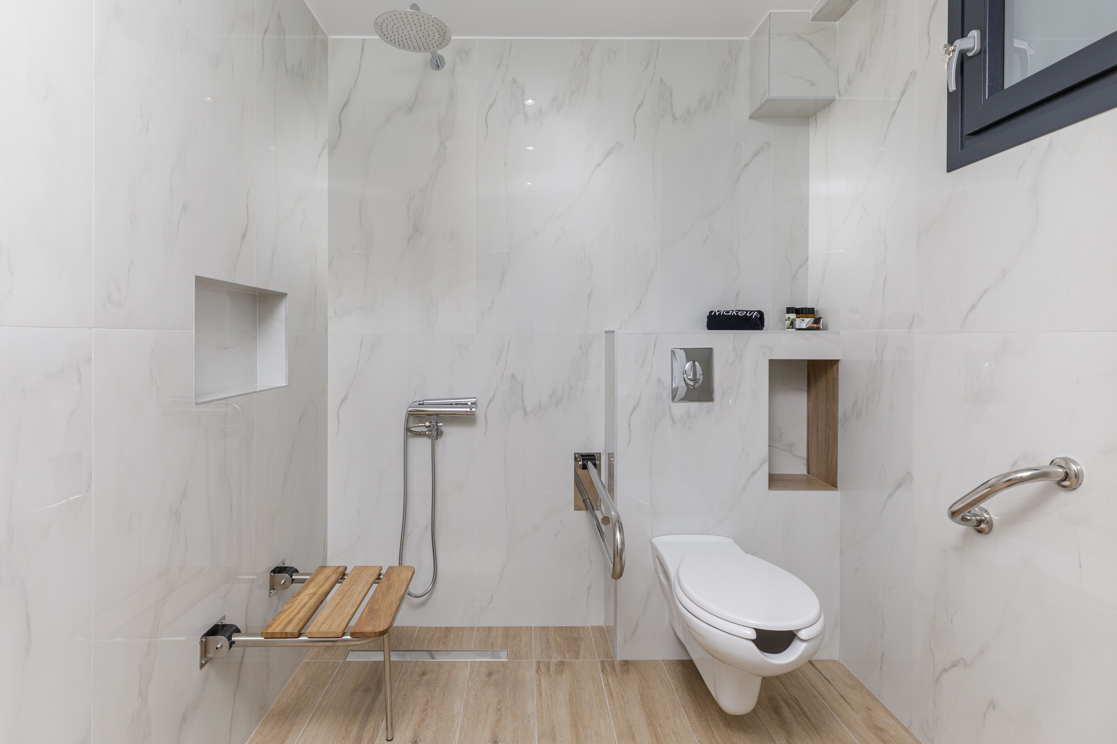 Une salle de bain moderne équipée d’une douche, de toilettes et d’un banc en bois.