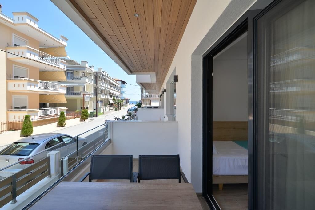 A balcony with a wooden ceiling, a bed, and a table with chairs.